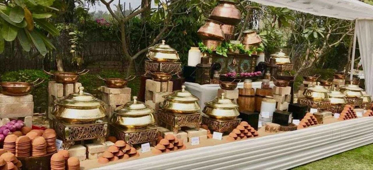 A rustic food display with earthen pots, fruit and woven baskets